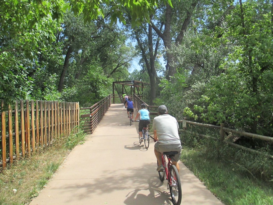Cyclists approaching a bridge on a bike trail.