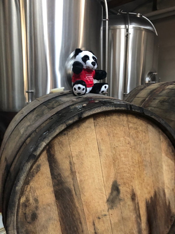 Small stuffed panda bear on a barrel.